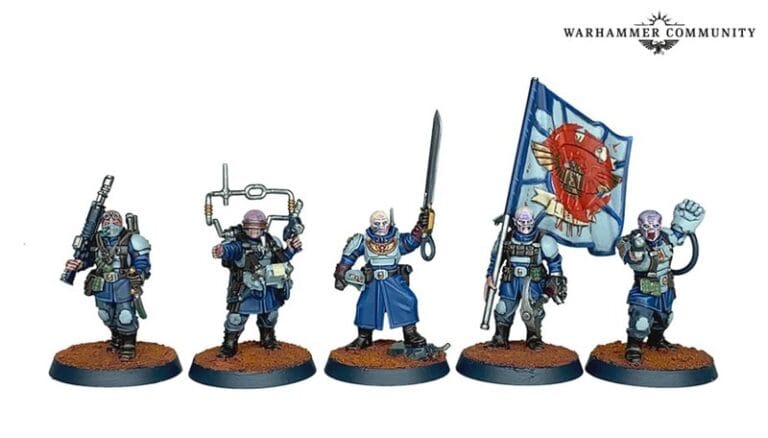Five Warhammer miniatures in blue-gray uniforms stand on a brown base, representing Cadian Shock Troops. One wields a rifle, another a tool; the third brandishes a sword, while others hold a scepter and a flag with a red eagle. Each pose is unique, showcasing intricate details and disciplined readiness.