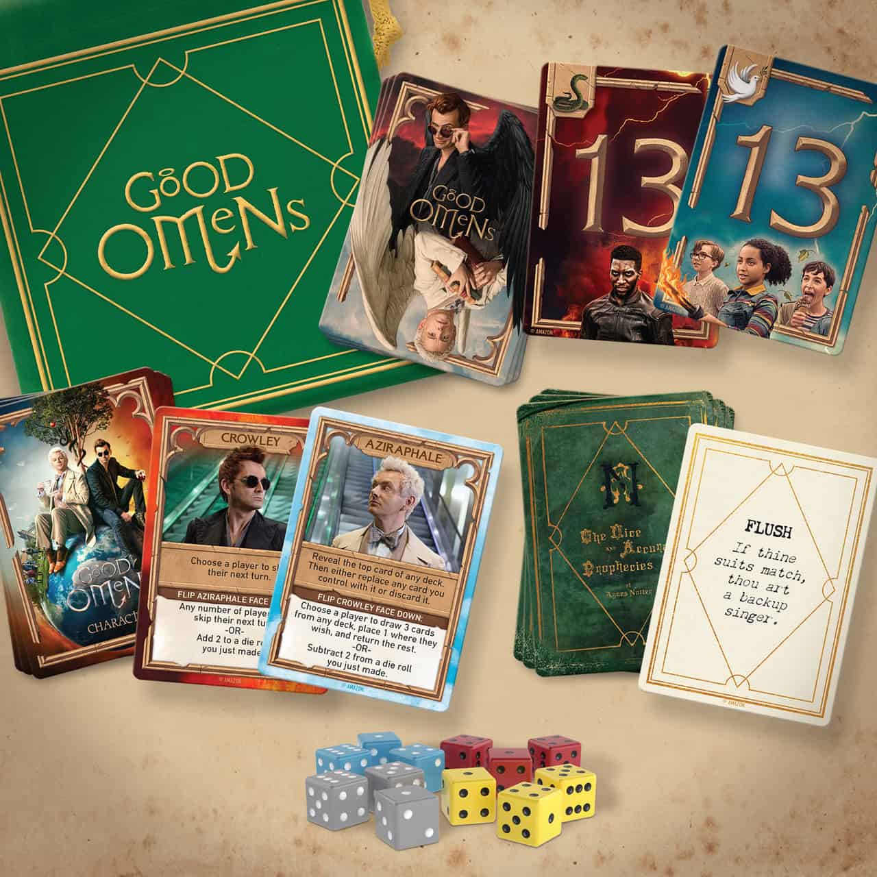 Board game components of "Good Omens: Ineffable Game" by Renegade Game Studios are displayed, including character cards, prophecy cards, a rulebook, and six colorful dice. The cards feature illustrations of characters and scenes, with the "Good Omens" logo adorning the box.